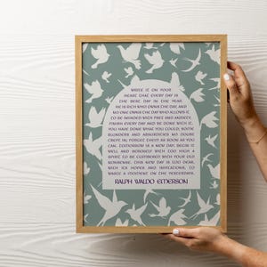 Op de afbeelding: Een ingelijst print met een citaat van Ralph Waldo Emerson op een lichtblauwe achtergrond met witte silhouetten van vogels. Het citaat luidt: "Schrijf het in je hart dat elke dag de beste dag van het jaar is. Hij is rijk die de dag bezit, en niemand bezit de dag die toestaat dat hij wordt binnengevallen door zorgen en angst. Maak elke dag af en wees er klaar mee. Je hebt gedaan wat je kon; er zijn ongetwijfeld wat fouten en absurditeiten ingeslopen; vergeet ze zo snel mogelijk. Morgen is een nieuwe dag; begin hem goed en rustig met een geest die te hoog is om te worden belast met je oude onzin. Deze nieuwe dag is te kostbaar, met zijn hoop en uitnodigingen, om een moment te verspillen aan het verleden."