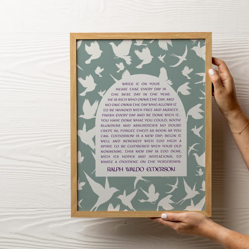 Op de afbeelding: Een ingelijst print met een citaat van Ralph Waldo Emerson op een lichtblauwe achtergrond met witte silhouetten van vogels. Het citaat luidt: "Schrijf het in je hart dat elke dag de beste dag van het jaar is. Hij is rijk die de dag bezit, en niemand bezit de dag die toestaat dat hij wordt binnengevallen door zorgen en angst. Maak elke dag af en wees er klaar mee. Je hebt gedaan wat je kon; er zijn ongetwijfeld wat fouten en absurditeiten ingeslopen; vergeet ze zo snel mogelijk. Morgen is een nieuwe dag; begin hem goed en rustig met een geest die te hoog is om te worden belast met je oude onzin. Deze nieuwe dag is te kostbaar, met zijn hoop en uitnodigingen, om een moment te verspillen aan het verleden."