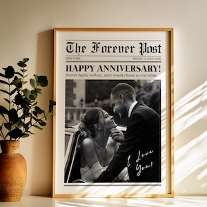 May include: A framed print with a newspaper-style design. The headline reads "The Forever Post" with the text "Happy Anniversary!" and a black and white photo of a couple. The words "I Love You!" are written in script.