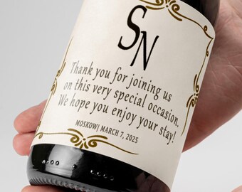 May include: A wine bottle with a white label featuring a gold decorative border and the initials "SN". The label also includes the text "Thank you for joining us on this very special occasion. We hope you enjoy your stay!" and the date "MOSKOWI MARCH 7, 2025".