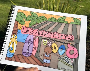 May include: A spiral-bound notebook with a colorful illustration of a beach scene. The cover reads "Lili's Adventures" and features surfboards, a teddy bear, and inflatable pool toys. The words "Birthday wishes" are also visible.