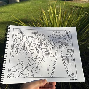 May include: A black and white coloring book page featuring a whimsical scene with a mushroom house, tulips, a teddy bear with a wand, and a snail pulling a carriage. The text "Welcome" is on a sign, and the text "Lili's Adventures" is in the corner.