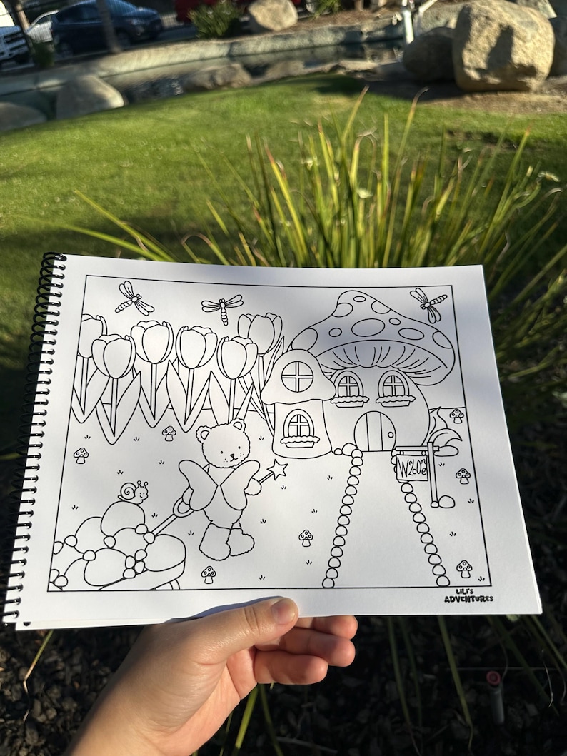 May include: A black and white coloring book page featuring a whimsical scene with a mushroom house, tulips, a teddy bear with a wand, and a snail pulling a carriage. The text "Welcome" is on a sign, and the text "Lili's Adventures" is in the corner.