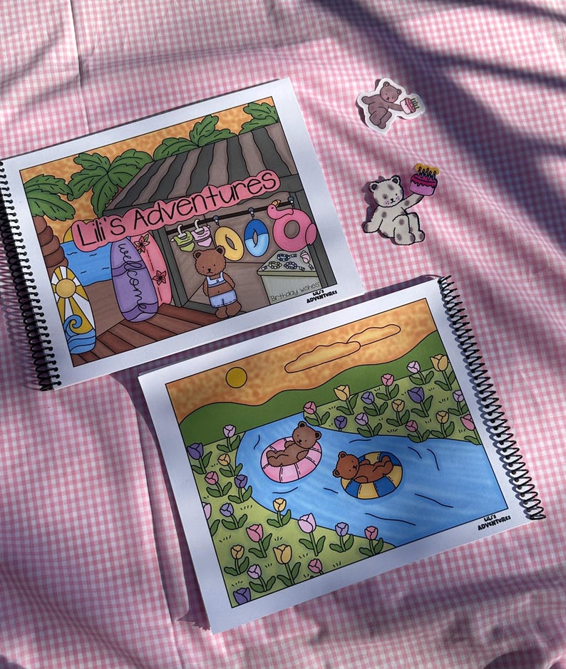 May include: Two spiral-bound notebooks with colorful illustrations of bears at the beach and in a river. The top notebook reads "Lili's Adventures" and features a bear at a beach stand. Two bear stickers are also visible.