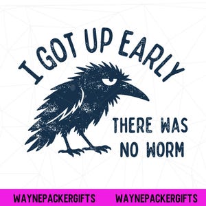 May include: A dark blue graphic illustration of a grumpy-looking crow with ruffled feathers. The text arched above reads I GOT UP EARLY and the text below reads THERE WAS NO WORM. The design has a distressed texture and is set on a white background.