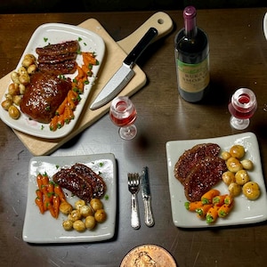 May include: Miniature dining scene featuring plates of steak, carrots, and potatoes. A bottle of wine, two wine glasses, a knife, and silverware are also present. A penny is included for scale. The food is arranged on a dark wooden surface.