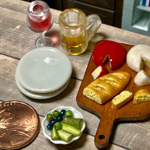 Puede incluir: Juego de comida y bebida en miniatura con queso rojo, queso blanco, baguette, aceitunas y bebidas. Incluye una copa de vino, una jarra de cerveza y dos platos pequeños. Se incluye una moneda como escala.