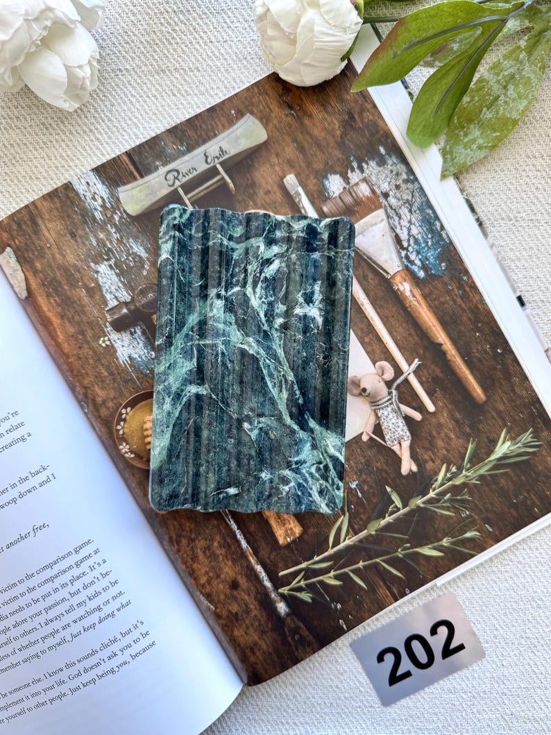 May include: A rectangular soap dish made of dark green marble with white veining. The dish has a ridged surface and is displayed on a magazine. The number "202" is visible in the bottom right corner.