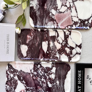 May include: Three rectangular trays featuring a polished white and deep purple marble pattern with intricate veining. The trays are arranged vertically, showcasing a smooth, glossy surface with distinct dark purple and white color variations.