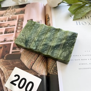 May include: A rectangular, green soap dish with a ridged design. The soap dish is made of a stone-like material and sits on an open magazine. The number "200" is on a white tag in the image.