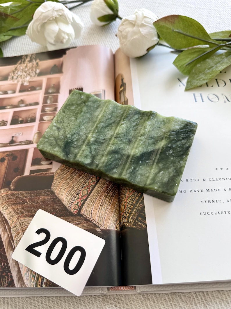 May include: A rectangular, green soap dish with a ridged design. The soap dish is made of a stone-like material and sits on an open magazine. The number "200" is on a white tag in the image.