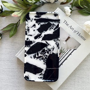May include: A rectangular tray featuring a high-contrast black and white marbled pattern with a glossy finish. The tray has rounded corners and a smooth, flat surface, showcasing an intricate, irregular design of dark black shapes against a white background.