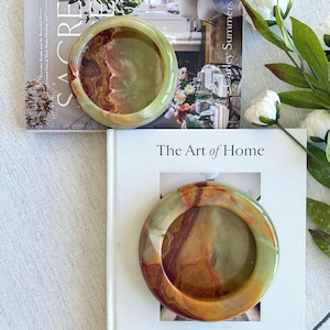 May include: A set of three ceramic mugs with a speckled, matte finish. The mugs are in shades of cream, light grey, and dark grey. Each mug has a simple, minimalist design, ideal for coffee or tea.