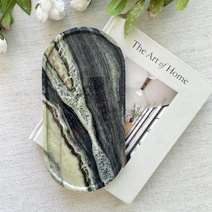 May include: An oval-shaped tray crafted from polished stone featuring a striking pattern of deep black, forest green, and creamy white veins. The surface is smooth and glossy, showcasing the natural variations and intricate mineral striations.