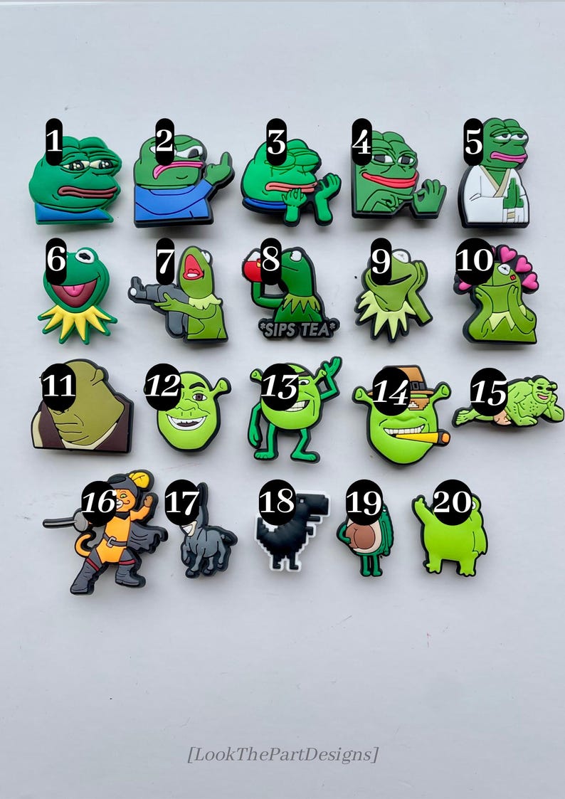 May include: Twenty colorful cartoon character shoe charms, including a frog drinking tea, a frog with a gun, a frog with hearts, a Shrek character with a cigar, and a cat in a knight costume.