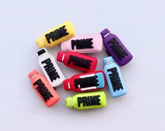 May include: A collection of colorful, miniature bottle-shaped charms. Each charm features the word "PRIME" in bold, black letters. The bottles come in various colors, including yellow, pink, purple, red, white, blue, and green.