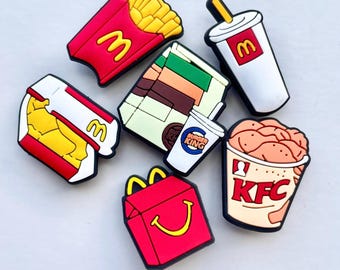 May include: A collection of colorful fast food-themed charms, including a red container of fries with a yellow "M" logo, a white cup with a yellow straw and "M" logo, and a KFC bucket.