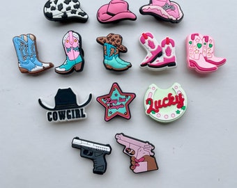 May include: A set of 12 colorful cowboy-themed shoe charms, including cowboy hats, boots, and a horseshoe with the word "Lucky" on it. There are also charms with a star and the text "Stay live Cowgirl" and a cowboy hat with the word "Cowgirl" on it.