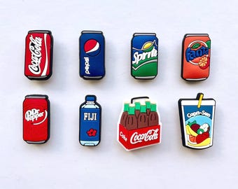 May include: A collection of colorful shoe charms featuring popular beverage brands. Includes Coca-Cola, Pepsi, Sprite, Fanta, Dr. Pepper, Fiji water, a Coca-Cola six-pack, and a Capri-Sun drink.