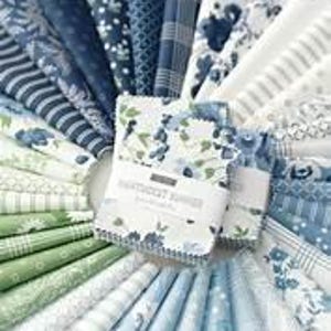 May include: A selection of fabric swatches in shades of blue, green, and white, fanned out to display various patterns. The fabrics include floral, striped, and polka dot designs. A central bundle of swatches features a floral pattern and the text "Sweetheart Summer".