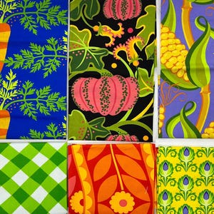 Pode incluir: Seis amostras de tecido com padrões diversos: cenouras laranja sobre azul, abóboras cor-de-rosa sobre preto, milho amarelo sobre roxo, xadrez vichy verde e branco, folhas florais laranja e vermelhas e um padrão geométrico amarelo com detalhes roxos.