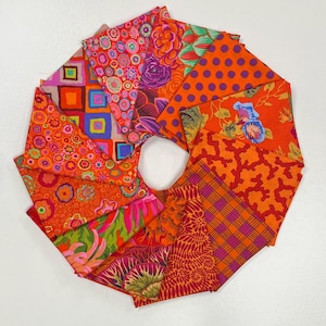 May include: A collection of orange fabric squares arranged in a circular pattern. The fabrics feature various designs, including floral, polka dots, geometric shapes, and plaid patterns. The color palette includes shades of orange, pink, purple, and green.