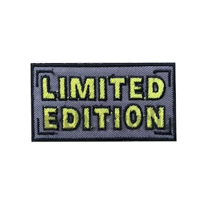 May include: A gray embroidered patch with black outlines and yellow lettering that reads "LIMITED EDITION".