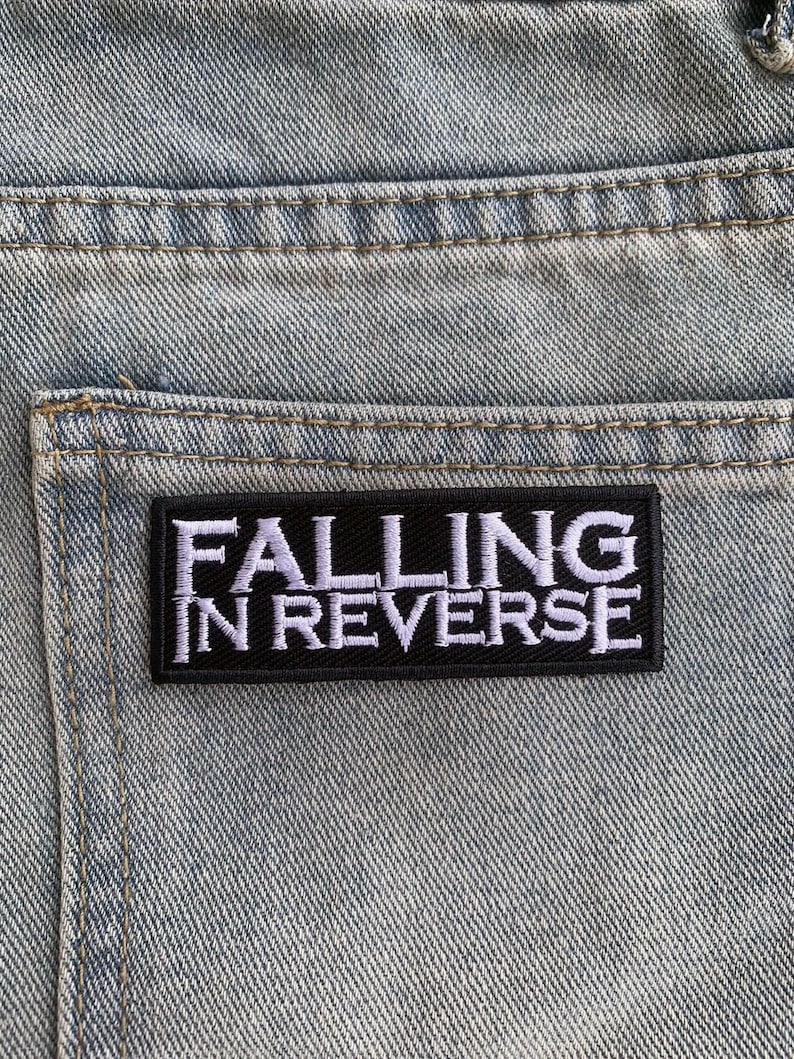 May include: Black and white embroidered patch with the text "Falling in Reverse" on a light blue denim background.