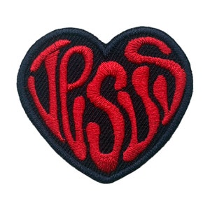 以下が含まれることがあります： 「PSST」という文字が書かれたハート型の赤い刺繍パッチ