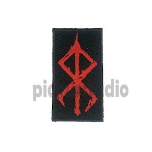 May include: Red embroidered symbol on a black patch. The symbol is a stylized rune with a vertical line in the center and four angled lines extending from the center.