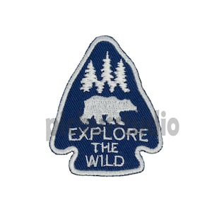 May include: Blue embroidered patch featuring a white bear, trees, and the text "Explore the Wild".