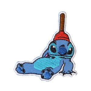 May include: Embroidered iron-on patch featuring a blue Stitch character from Lilo & Stitch wearing a red plunger on its head. The character is lying down with its arms and legs outstretched.