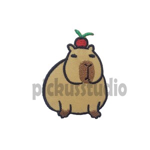 Peut inclure: Patch brodé thermocollant représentant un capybara brun portant une cerise rouge et verte sur la tête.