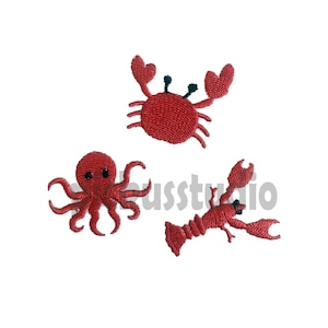 Może przedstawiać: Trzy czerwone haftowane łatki do prasowania przedstawiające kraba, ośmiornicę i homara.