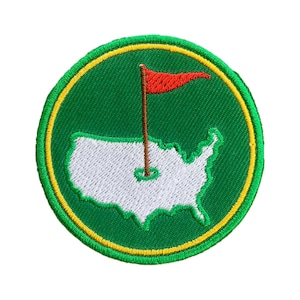 Könnte beinhalten: Ein gestickter Aufnäher mit grünem und gelbem Rand, einer weißen Umrandung der Vereinigten Staaten, einer roten Flagge und einem braunen Golfschläger.