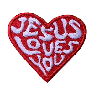 May include: Red heart-shaped patch with white embroidered text that reads "JESUS LOVES YOU".
