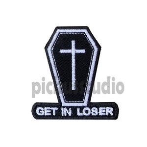 Könnte beinhalten: Schwarzer und weißer gestickter Aufnäher mit einem Sarg- und Kreuzdesign. Der Text "GET IN LOSER" befindet sich unter dem Sarg.