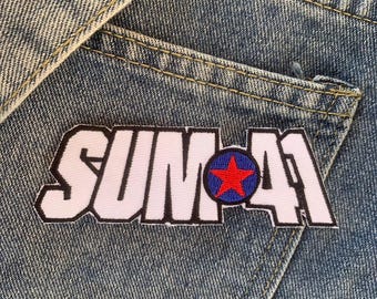Könnte beinhalten: Ein weißer und rosa gestickter Patch mit dem Text "SUM 41" in schwarzen Buchstaben und einem roten Stern in einem blauen Kreis.
