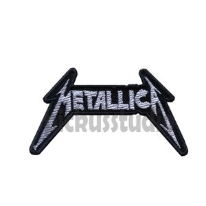 May include: Black and white embroidered patch with the word "Metallica" in a stylised font. The patch is shaped like a lightning bolt.