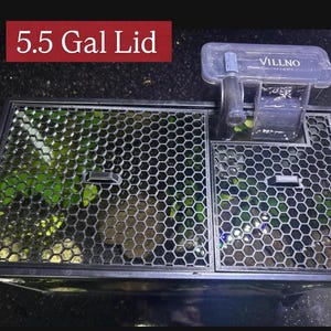 May include: A black aquarium lid with a honeycomb pattern, featuring a built-in filter system. The lid is labeled "5.5 Gal Lid" in white text on a red background. A clear plastic filter is attached to the lid, with the brand name "VILLNO" visible.