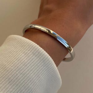 Peut inclure: Un bracelet argent&eacute; en forme de jonc port&eacute; au poignet.