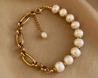 May include: A gold chain bracelet with a row of white pearls. The bracelet has a lobster clasp closure.