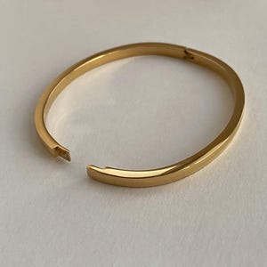 Peut inclure: Un bracelet jonc dor&eacute; avec une ouverture &agrave; charni&egrave;re.