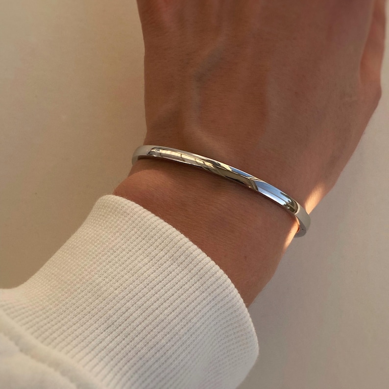 Peut inclure: Un bracelet jonc argent&eacute; port&eacute; au poignet. Le bracelet est simple et &eacute;l&eacute;gant, avec une finition polie.