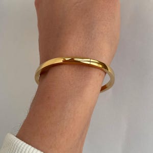 Peut inclure: Un bracelet jonc dor&eacute; &agrave; la finition simple et polie.