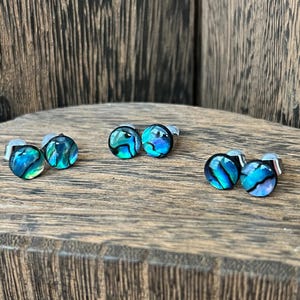 May include: Three pairs of iridescent blue and green abalone shell stud earrings with silver posts.