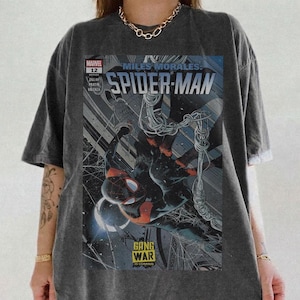 Op de afbeelding: Donkergrijs t-shirt met een Spider-Man stripboekcover. De afbeelding bevat de tekst "Miles Morales: Spider-Man" en "Gang War", met een dynamische illustratie van de superheld.