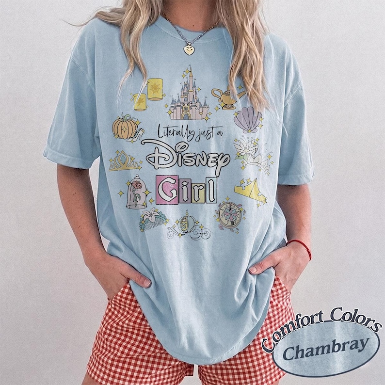 Op de afbeelding: Lichtblauw T-shirt met de tekst "Literally just a Disney Girl" en diverse Disney-thema graphics. Het shirt heeft korte mouwen en wordt gecombineerd met een rood-witte geruite short.
