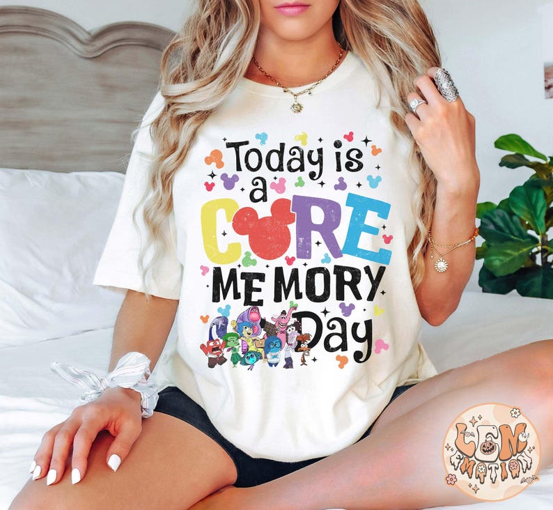 以下が含まれることがあります： 「Today is a CORE MEMORY Day」というカラフルなグラフィックがプリントされた白いTシャツ。ミッキーマウスの頭と映画「インサイド・ヘッド」のキャラクターが描かれています。