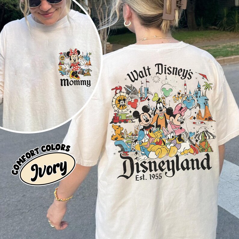 Puede incluir: Camiseta de manga larga color marfil con un gr&aacute;fico de Mickey y Minnie Mouse, y otros personajes de Disney. La parte trasera de la camiseta presenta el texto "Walt Disney's Disneyland Est. 1955". La parte delantera de la camiseta tiene la palabra "Mommy".